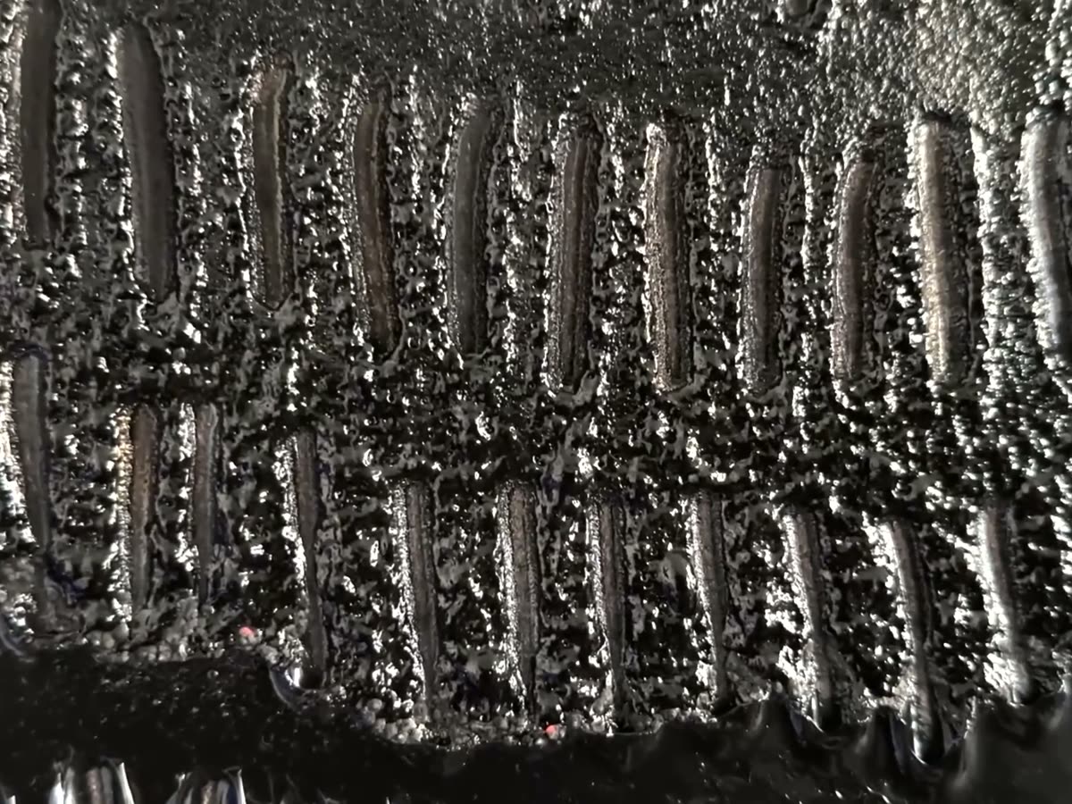 A close view of thick black paint, ridged and pooled